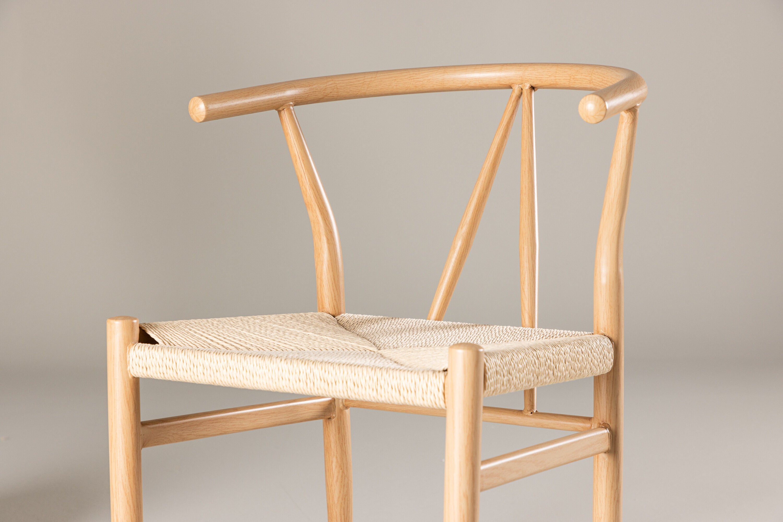 Venture Home Alfons Dining Chair, ett minimalistiskt trästycke med böjt ryggstöd och beige repsits, sticker ut mot en neutral bakgrund. Dess moderna design har rena linjer och en naturlig finish, som visar upp enkelhet och elegans.